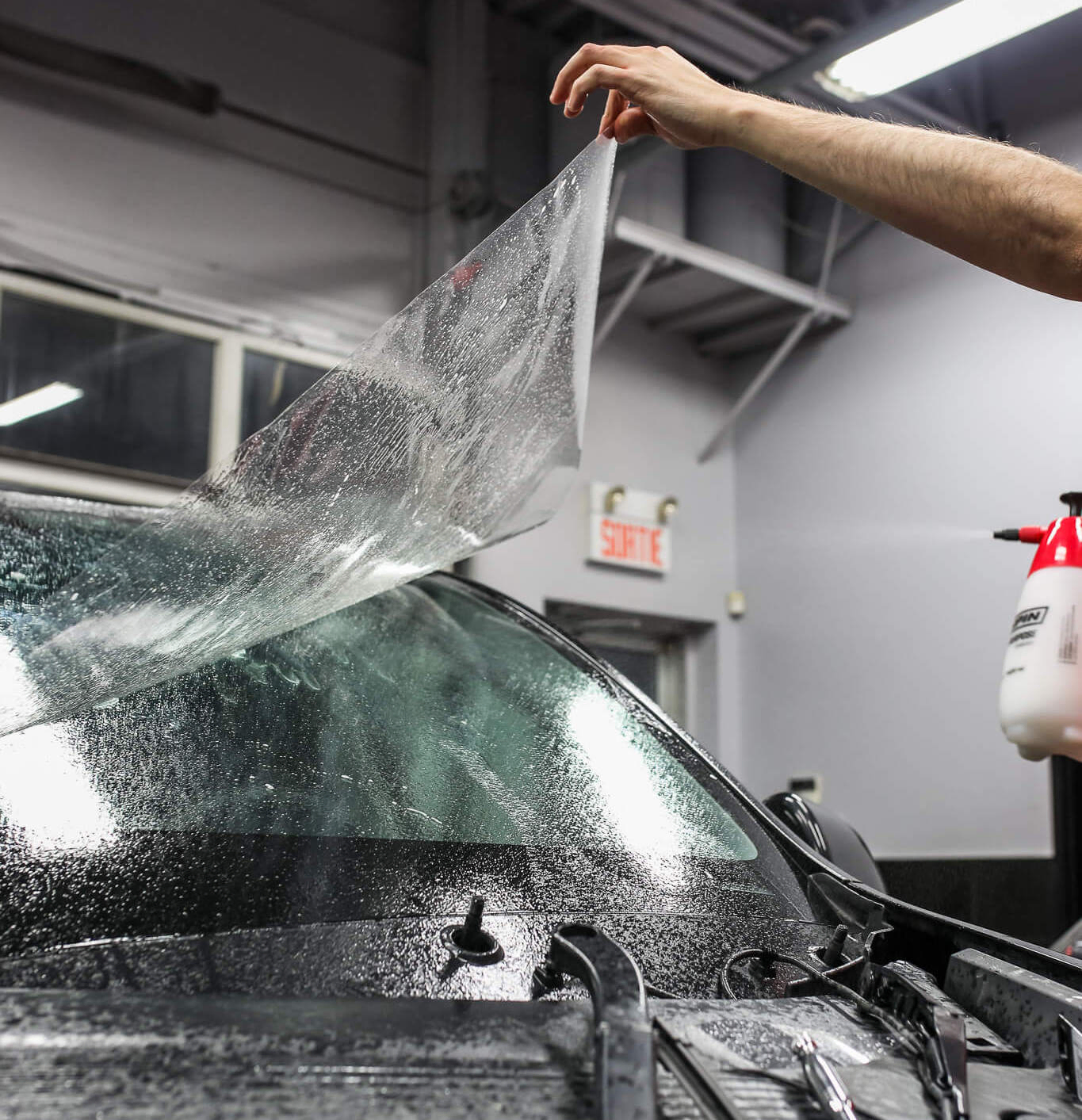 Technician installing ExoShield windshield protection film on a vehicle to prevent rock chips and cracks at Clear Cut Glass and Tint in Glendale, Arizona.