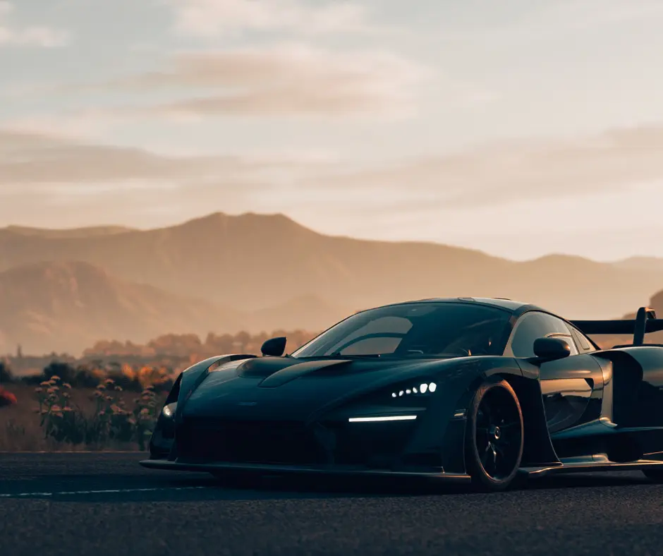 Black exotic sports car parked on an open road at sunset with mountains in the background, used to illustrate premium vehicle protection services such as window tint, paint protection film, and ceramic coating.