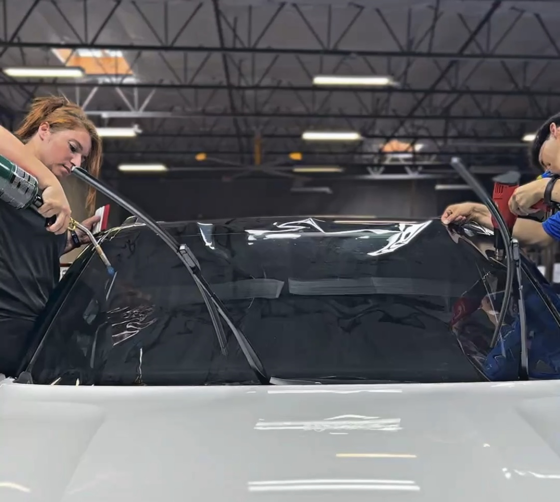 Technicians installing a new windshield on a vehicle inside the Clear Cut Glass and Tint shop