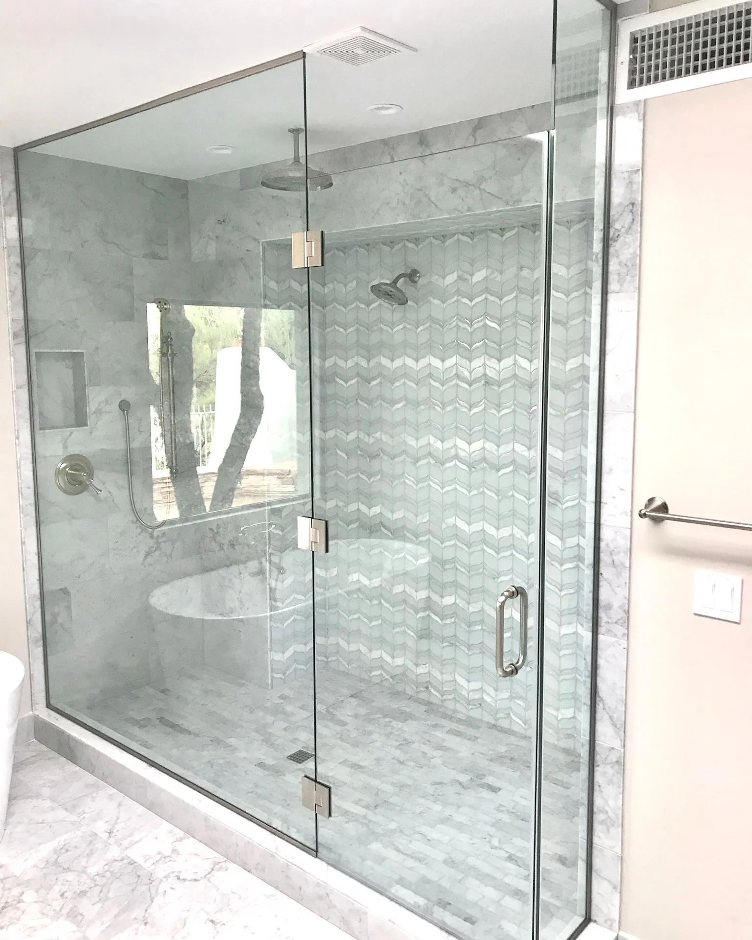 Frameless Glass Shower Enclosure with Marble Tile | Clear Cut Glass and Tint Frameless glass shower enclosure with marble tile walls, patterned accent tile, and brushed hardware in an Arizona home, installed by Clear Cut Glass and Tint