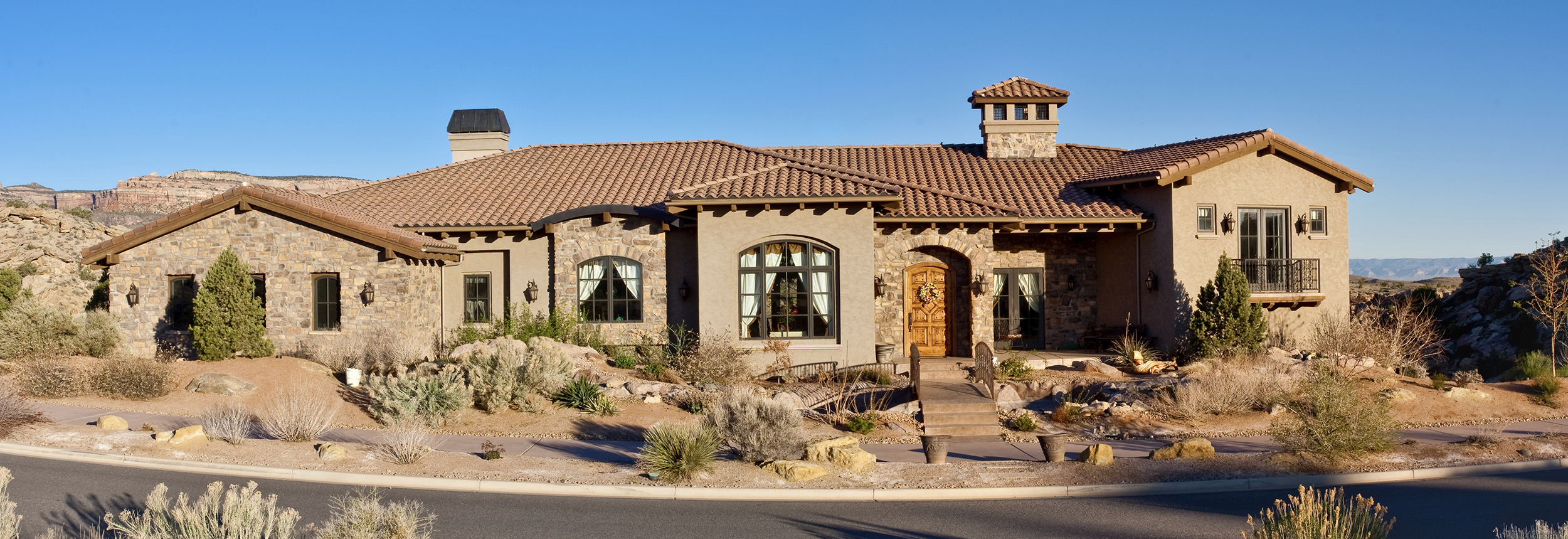 Luxury desert home with stone exterior and large custom windows in an Arizona landscape, featuring residential glass work by Clear Cut Glass and Tint