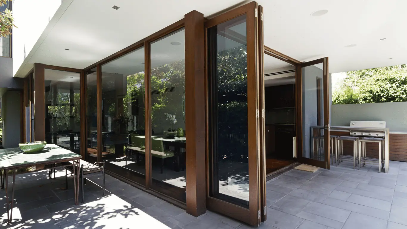 Residential folding glass door system creating seamless indoor-outdoor living with large glass panels and custom framing