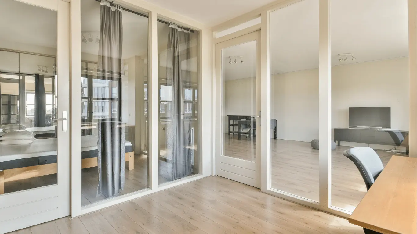 Studio apartment featuring residential interior glass partitions used to separate living and sleeping areas while maintaining natural light