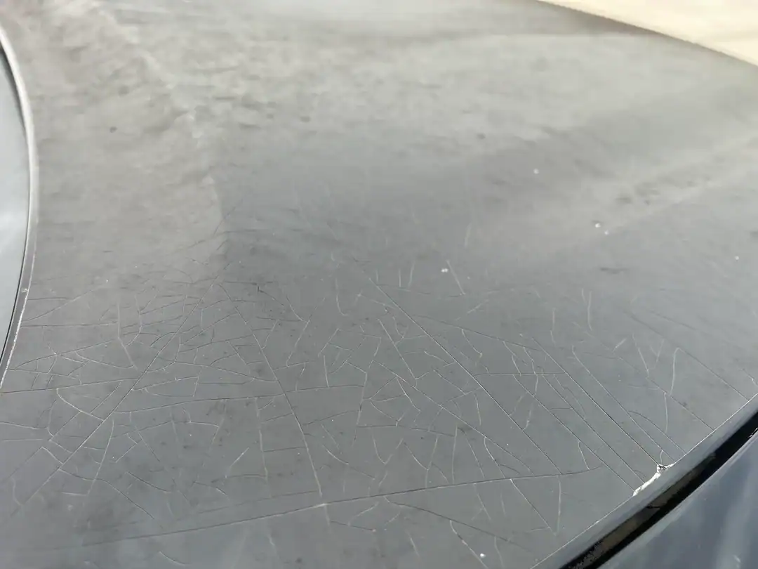 Cracked and dried paint protection film showing severe failure from prolonged sun exposure in Arizona