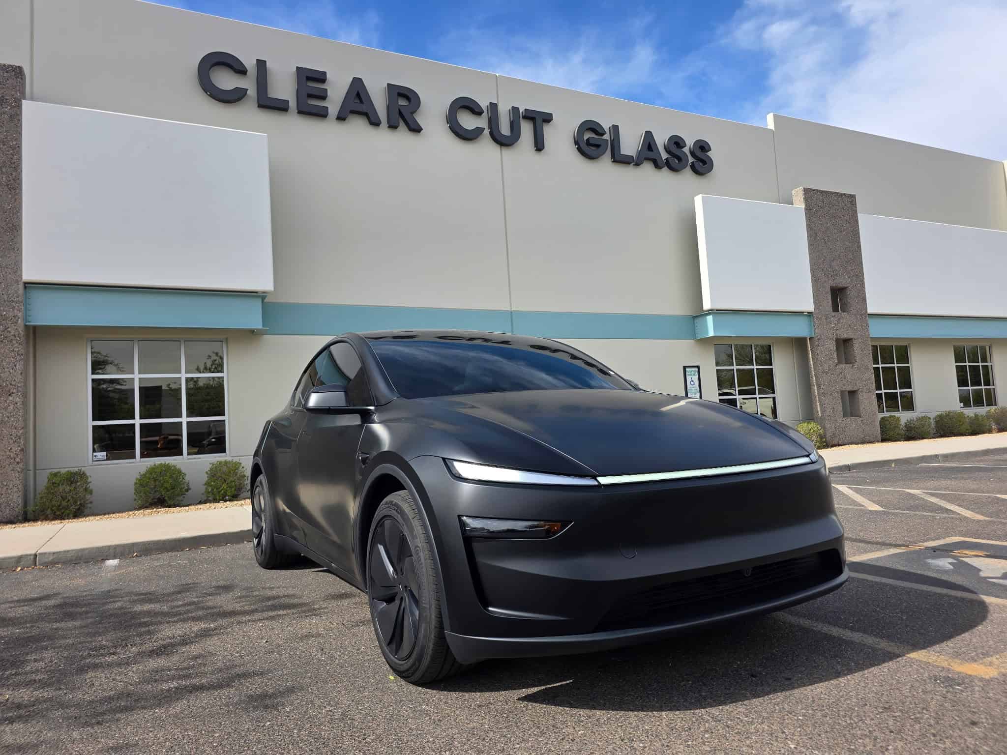 Tesla with matte paint protection film parked outside Clear Cut Glass and Tint in Arizona under bright sunlight