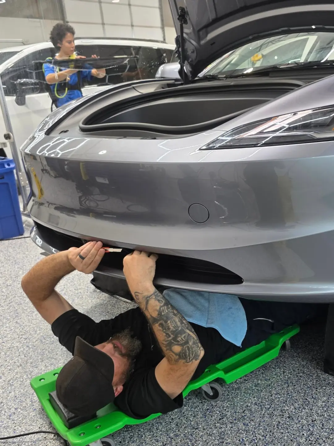 Installer custom fitting paint protection film around the lower front bumper of a Tesla